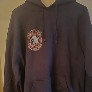 May include: Black hooded sweatshirt with a red circle logo featuring a Native American headdress and the words "Redrum Records & The People".