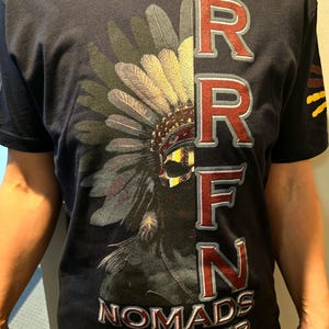 May include: A navy blue t-shirt with a graphic of a Native American headdress and the text "RRFN NOMADS CHAPTER" printed in red and white.