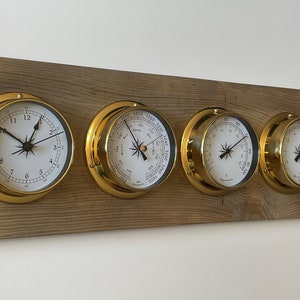 May include: A set of four brass nautical-style clocks mounted on a wooden board. The clocks include a clock face, a barometer, a thermometer, and a hygrometer.