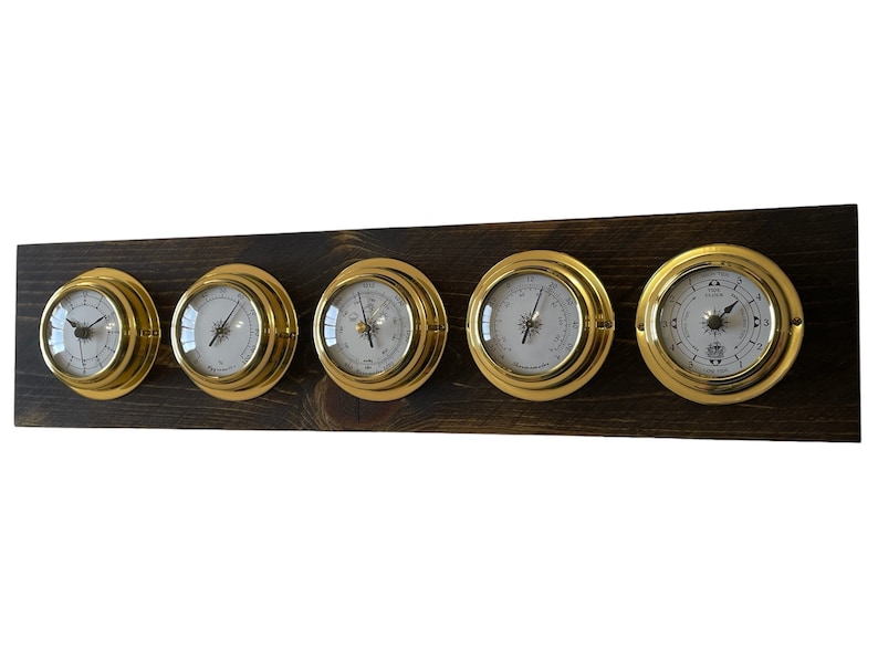 Puede incluir: Un conjunto de cinco indicadores anal&oacute;gicos de color dorado montados en una placa de madera marr&oacute;n oscuro. Los indicadores tienen caras blancas con agujas y marcas negras.