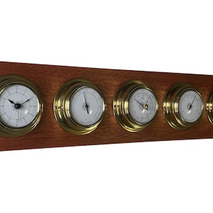 Op de afbeelding: Een houten wandklokset met vijf messingkleurige wijzerplaten. De wijzerplaten omvatten een klok, een barometer, een thermometer en twee andere meters.