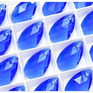 Könnte beinhalten: Nahaufnahme einer Schale mit blauen Kristall-Tropfenanhängern mit einem Loch oben zum Aufziehen.