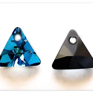 May include: Two triangle-shaped crystal pendants with a hole at the top for stringing. One pendant is a dark blue color and the other is black.
