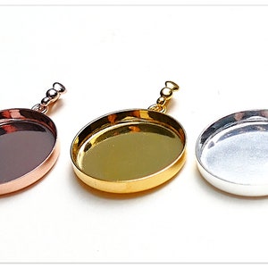 Può includere: Tre vassoi rotondi per ciondoli in diverse finiture metalliche: rame, oro e argento. Ogni vassoio ha una superficie liscia e lucida e un'anellina con tre piccole perle.