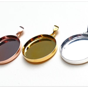 May include: Three oval-shaped pendant trays in different metal finishes: rose gold, gold, and silver. Each tray has a smooth, shiny surface and a loop at the top for attaching a chain.