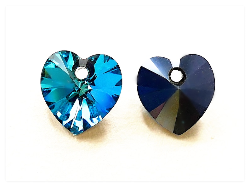May include: Two heart-shaped crystal pendants, one in a vibrant teal blue and the other in a deep, rich black. Both pendants have a small hole at the top for stringing.