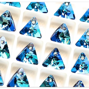 May include: A collection of blue triangle-shaped crystal beads with a hole at the top for stringing. The beads are arranged in a grid pattern on a white background.