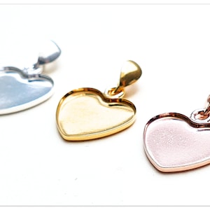 Puede incluir: Tres bandejas de colgantes en forma de corazón en plata, oro y oro rosa. Cada bandeja tiene una superficie lisa y brillante y un bucle en la parte superior para sujetar una cadena.