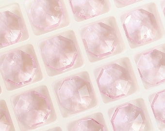 May include: A close-up view of a tray of pink octagon-shaped crystal beads. The beads are arranged in a grid pattern and are all the same size.