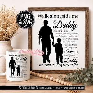 May include: A white ceramic mug and a framed sign featuring a black silhouette of an adult and a child holding hands. The text reads: Walk alongside me Daddy hold my hand I have so many things to learn that I don't yet understand.