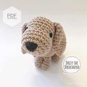 May include: Crochet pattern for a beige dachshund amigurumi toy named Daisy. The pattern is available as a PDF download. The image shows the finished crocheted toy.