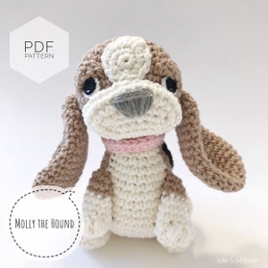 Może przedstawiać: Wzór na szydełku na brązowego i białego psa z różowym kołnierzem. Wzór nazywa się "Molly the Hound" i jest dostępny jako plik PDF do pobrania.
