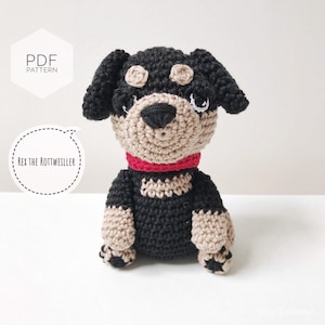 Könnte beinhalten: Häkelanleitung für einen Rottweiler-Hund namens Rex. Das Muster ist als PDF-Download erhältlich. Der gehäkelte Hund ist schwarz und braun mit einem roten Halsband.