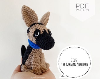May include: Crochet pattern for a German Shepherd dog named Zeus. The pattern is available as a PDF download. The dog is brown and black with a blue collar.