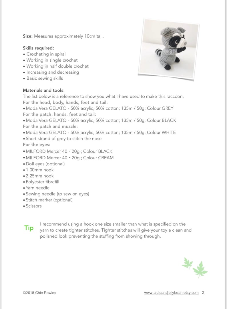 May include: A crochet pattern for making a raccoon amigurumi toy. The pattern includes instructions for crocheting the head, body, hands, feet, and tail using Moda Vera Gelato yarn in grey, black, and white. The pattern also includes instructions for crocheting the eyes using Milford Mercer yarn in black and cream.