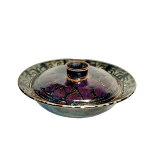 May include: A ceramic serving dish with a lid. The dish is decorated with a dark purple and black floral pattern and a gold rim. The lid has a small knob on top.
