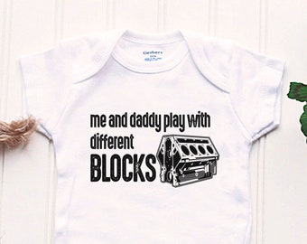May include: White baby onesie with black text that reads "Me and daddy play with different BLOCKS" and a black and white image of an engine block.
