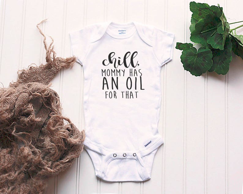 May include: White baby onesie with black text that reads "Chill, Mommy has an oil for that."