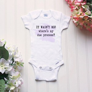May include: White baby onesie with a purple watercolor background and the text "IT WASN'T ME! where's my due process?"