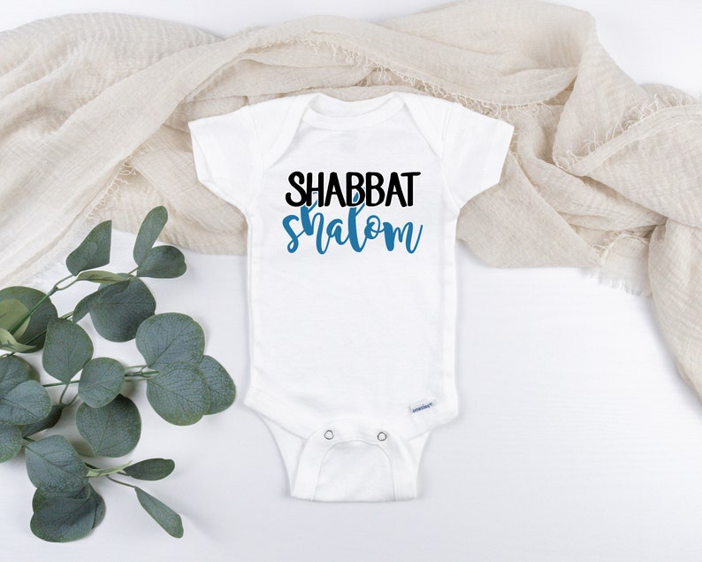 May include: White baby onesie with the text "Shabbat Shalom" in black and blue lettering.