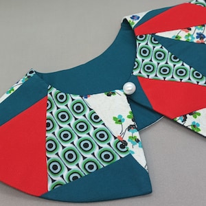 Könnte beinhalten: Ein Kragen aus Patchwork-Stoff in den Farben Teal, Rot, Weiß und Grün mit einem Perlenknopf.