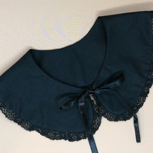 May include: A black lace collar with a black satin ribbon tie. The collar is made of a soft fabric and has a delicate lace trim.
