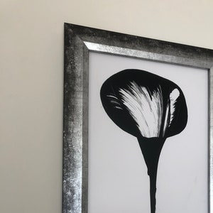 Könnte beinhalten: Schwarzweißes abstraktes Gemälde einer Blume in einem silbernen Rahmen.