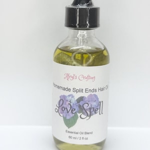 May include: A clear glass dropper bottle filled with a light yellow liquid. The white label reads Afryl's Crafting, Homemade Split Ends Hair Oil, Love Spell, Essential Oil Blend, and 60 ml / 2 fl oz, featuring an image of purple hydrangea flowers.