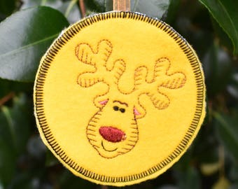 May include: Yellow felt Christmas bauble with an embroidered reindeer face. The reindeer has a red nose and brown antlers.