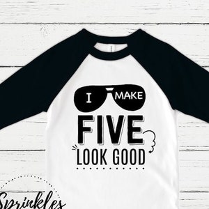 May include: White and black baseball tee shirt with the text "I make five look good" and a pair of sunglasses graphic. The text "Sprinkles and Jam" is printed on the bottom of the shirt.