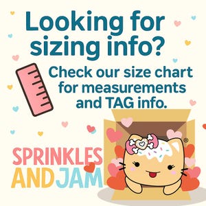 The image is a colorful advertisement featuring a cartoon cat with a sprinkles and jam theme, surrounded by hearts. The text invites viewers to check a size chart for measurements and tag information, and the image is described as a "Sprinkles and Jam" advertisement.
