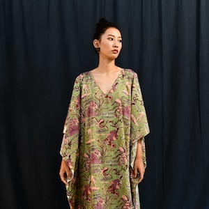 May include: A long, green and purple kaftan with a floral print featuring sea creatures. The kaftan has a V-neck and wide sleeves.