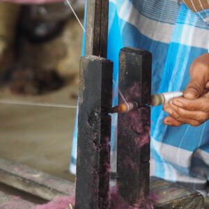 Hands of Indian artisan spinning linen using traditional methods