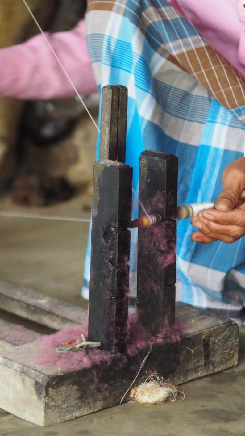 Hands of Indian artisan spinning linen using traditional methods