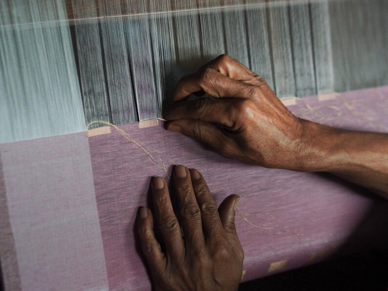 Hands of Indian artisan weaving linen on traditional handloom