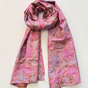 Pretty upcycled sari silk kantha scarf looped on a white background, the scarf has an abstract print and is handmade with tiny running stitches embroidered all over.