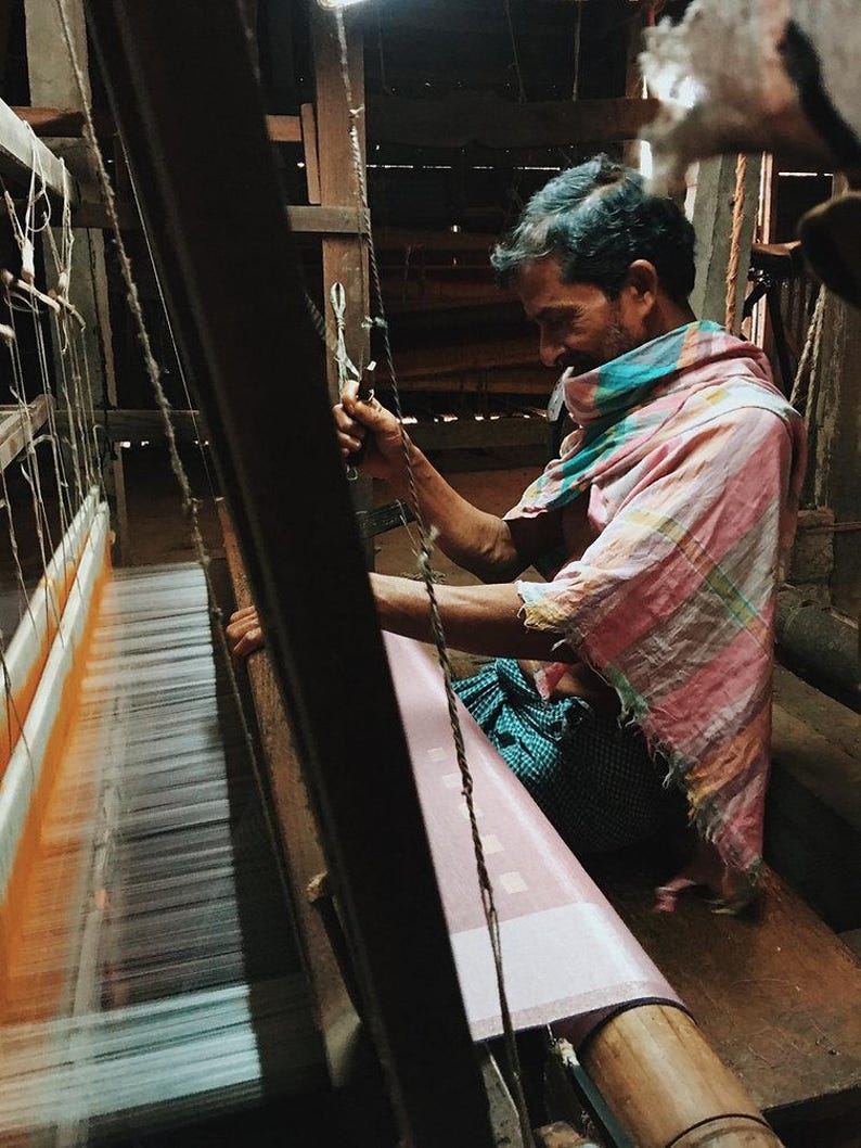 Indian artisan at work weaving linen kaftan on traditional handloom.