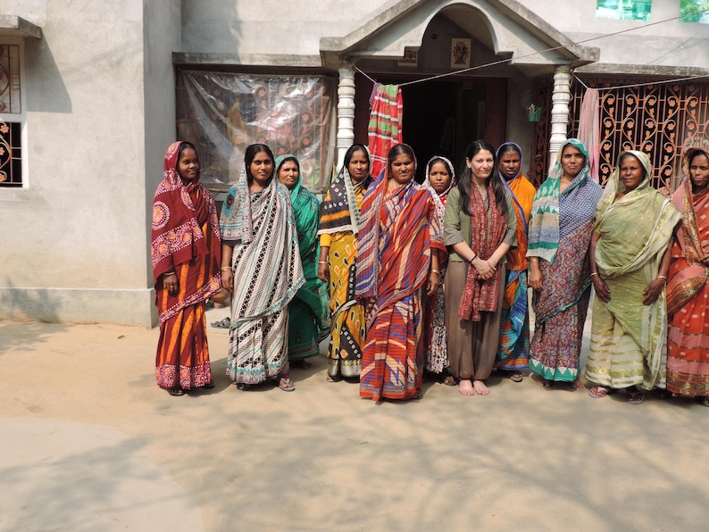 Group shot of Indian kantha artisan women with founder of Jewelled Buddha clothing brand Harjit Sohotey-Khan in village in Bengal