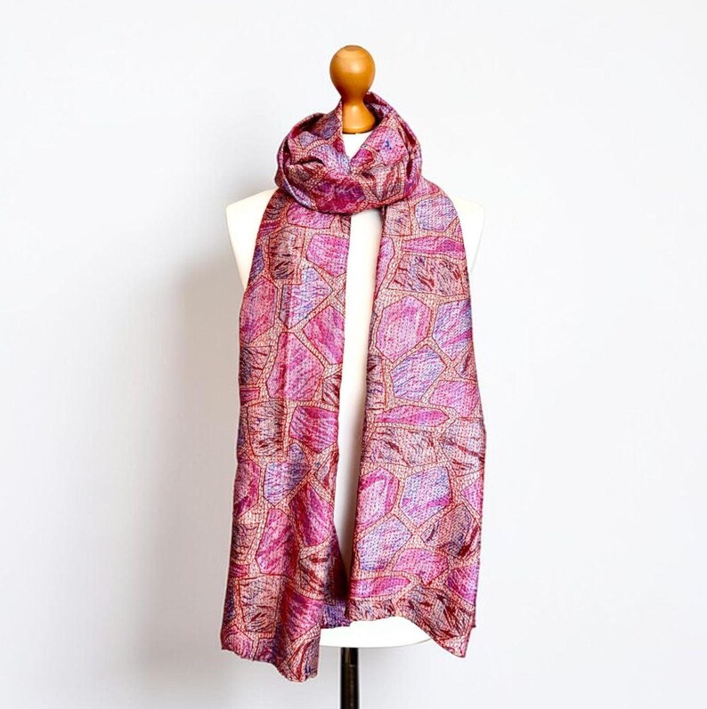 Colourful abstract print pink silk scarf draped over a white mannequin against a plain background
