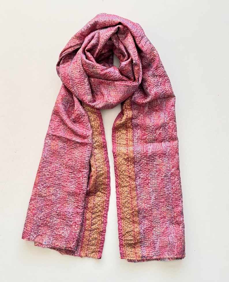 Upcycled sari silk pink and gold scarf looped on a plain white background, the scarf is handmade from vintage preloved sari silk and upcycled with tiny running stitches called Kantha stitch to create a lightly quilted texture. The scarf has a delicate floral print and embellished zari thread border running all the way down.