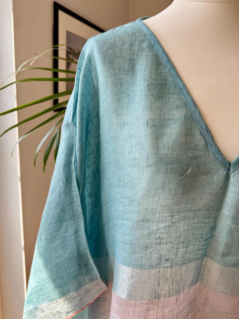 May include: A light blue linen top with a V-neck and a pink and white striped bottom.