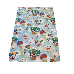 May include: A blue and white twin-sized bed sheet with a colorful print of Mickey Mouse, Donald Duck, Goofy, and other Disney characters flying in hot air balloons. The sheet features the text "When You Wish Upon A Star".