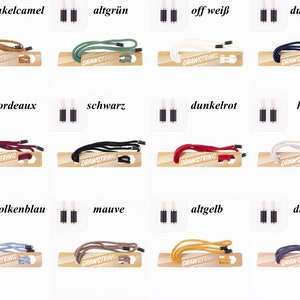 Könnte beinhalten: Ein Set mit 12 verschiedenen farbigen Kordeln mit Metallenden. Die Farben sind: Dunkelbraun, Grün, Off-White, Dunkelblau, Burgunderrot, Schwarz, Dunkelrot, Hellgrau, Hellblau, Mauve, Gelb und Dunkelgrau.