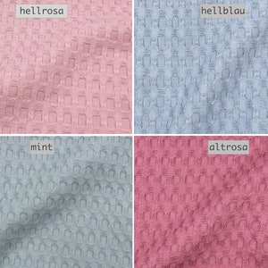 Może przedstawiać: Cztery próbki tkaniny w różnych kolorach: jasnoróżowy, jasnoniebieski, jasnoszary i ciemnoróżowy. Każda próbka ma fakturę wafelkową.