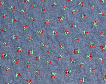 Könnte beinhalten: Ein blauer Jeansstoff mit einem sich wiederholenden Muster aus roten Kirschen mit grünen Stielen und Blättern.