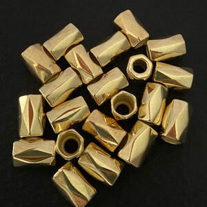 Könnte beinhalten: Eine Gruppe von 15 goldfarbenen Metallperlen mit einem facettierten Design. Die Perlen haben ein Loch in der Mitte zum Aufziehen.