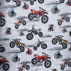 Könnte beinhalten: Ein grauer Stoff mit einem sich wiederholenden Muster aus farbenfrohen Motocross-Motorrädern, Helmen und der Nummer 71. Die Motorräder sind in verschiedenen Farben gehalten, darunter Rot, Blau, Gelb und Schwarz. Die Helme sind blau, weiß und orange.