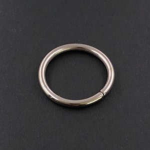 Könnte beinhalten: Ein silberner Metallring, auch bekannt als Schlüsselring oder Sprungring, ist eine einfache kreisförmige Form mit einer kleinen Lücke.