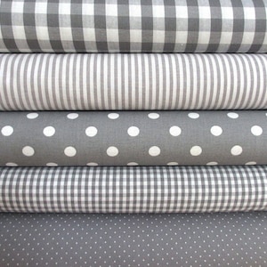 Könnte beinhalten: Fünf Rollen Stoff in verschiedenen Mustern. Der Stoff ist grau mit weißen Punkten, weißen Streifen und weißem Gingham.