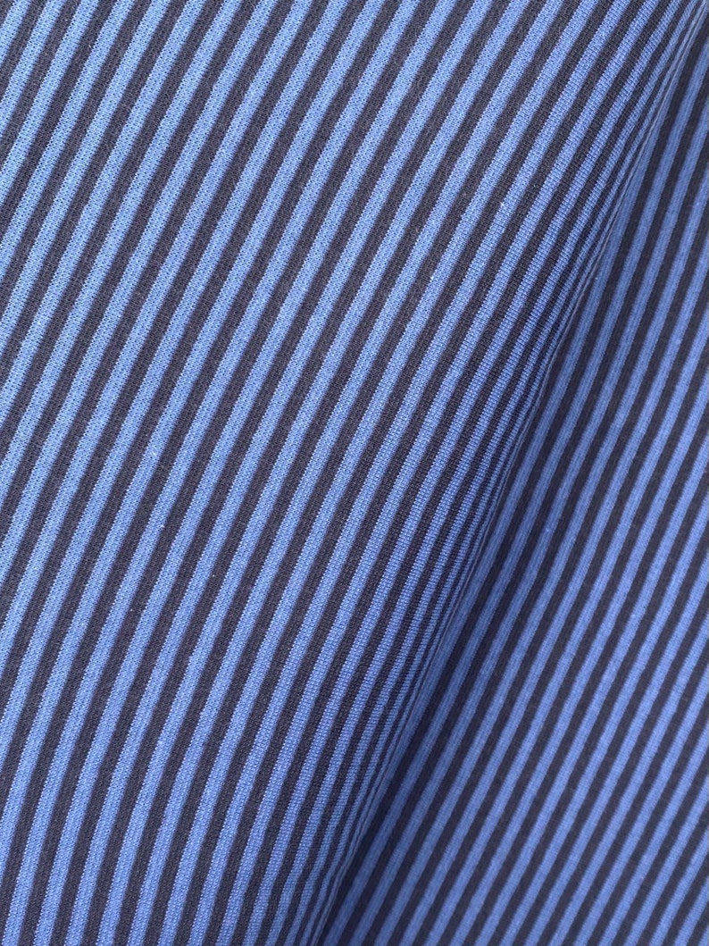 May include: Close-up of a blue and black striped fabric. The fabric has a diagonal pattern and a soft, textured feel.